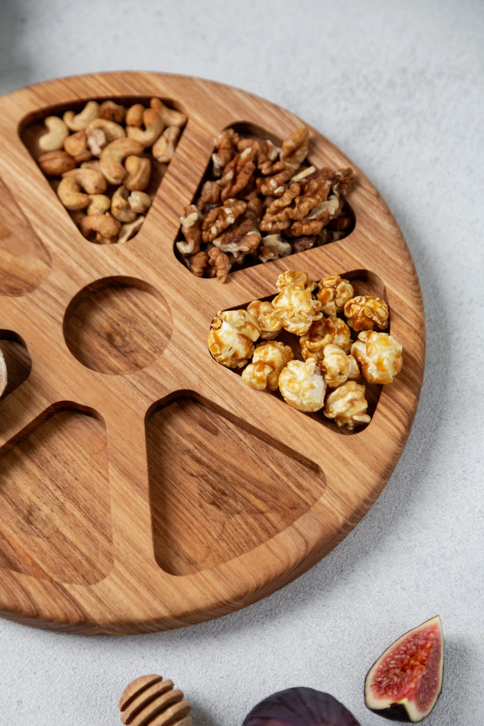 Rundes Serviertablett aus Eiche „Blume“ – Ø 30 cm, 7 Fächer Nahaufnahme der Fächer mit Walnüssen, Cashewkernen und Popcorn